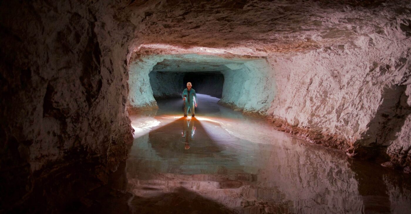 a miner inspecting flood water levels in an underground mine