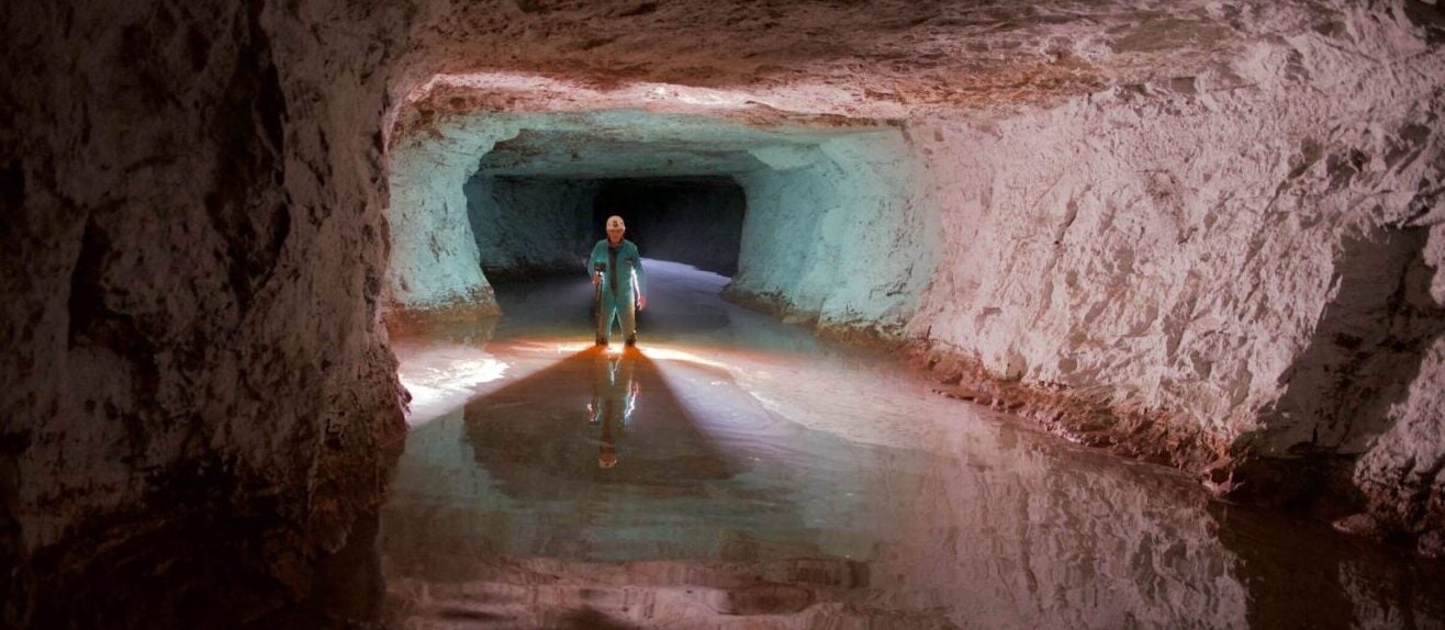 a miner inspecting flood water levels in an underground mine