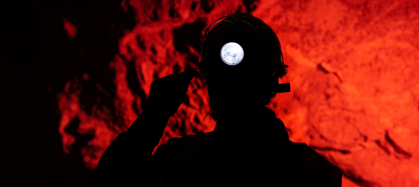 Silhouette of miner underground with cap light in