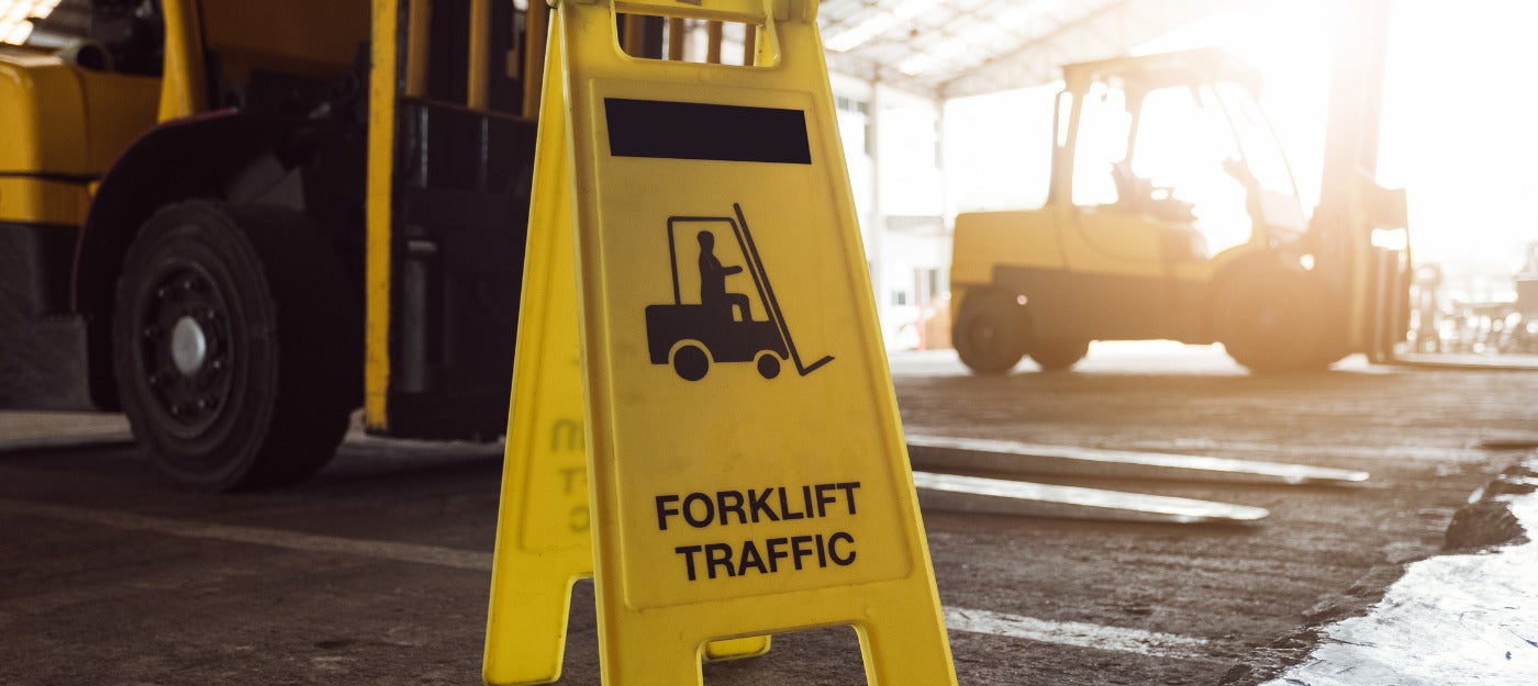 Forklift safety sign in warehouse with forklift in the background