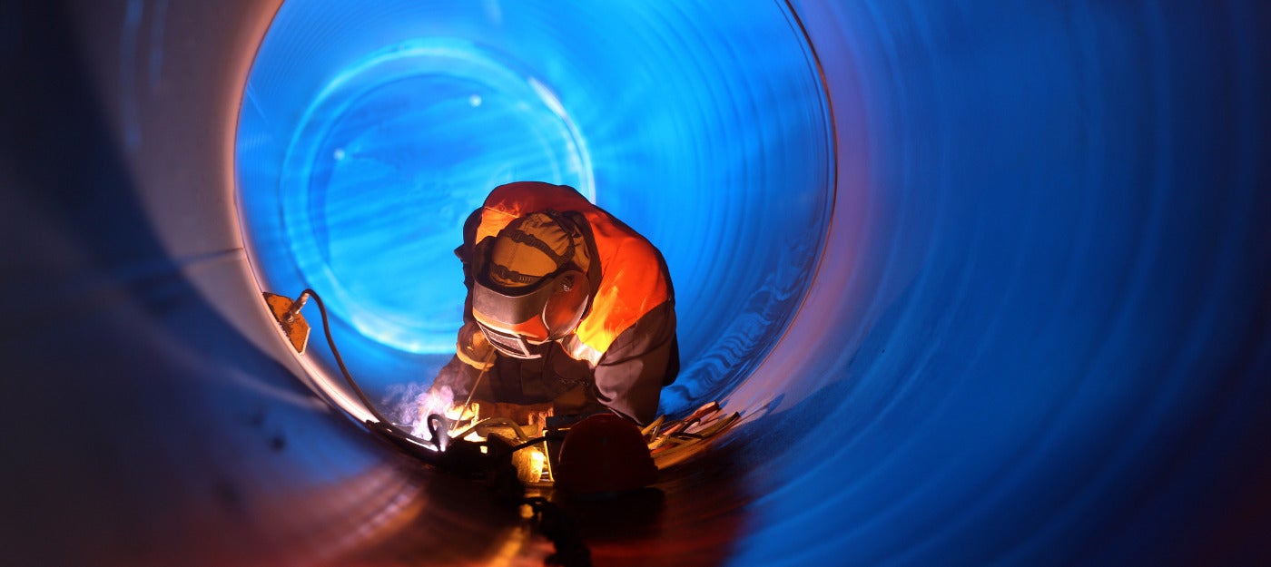 Man working in microtunnel constructing pipeline and wearing safety gear