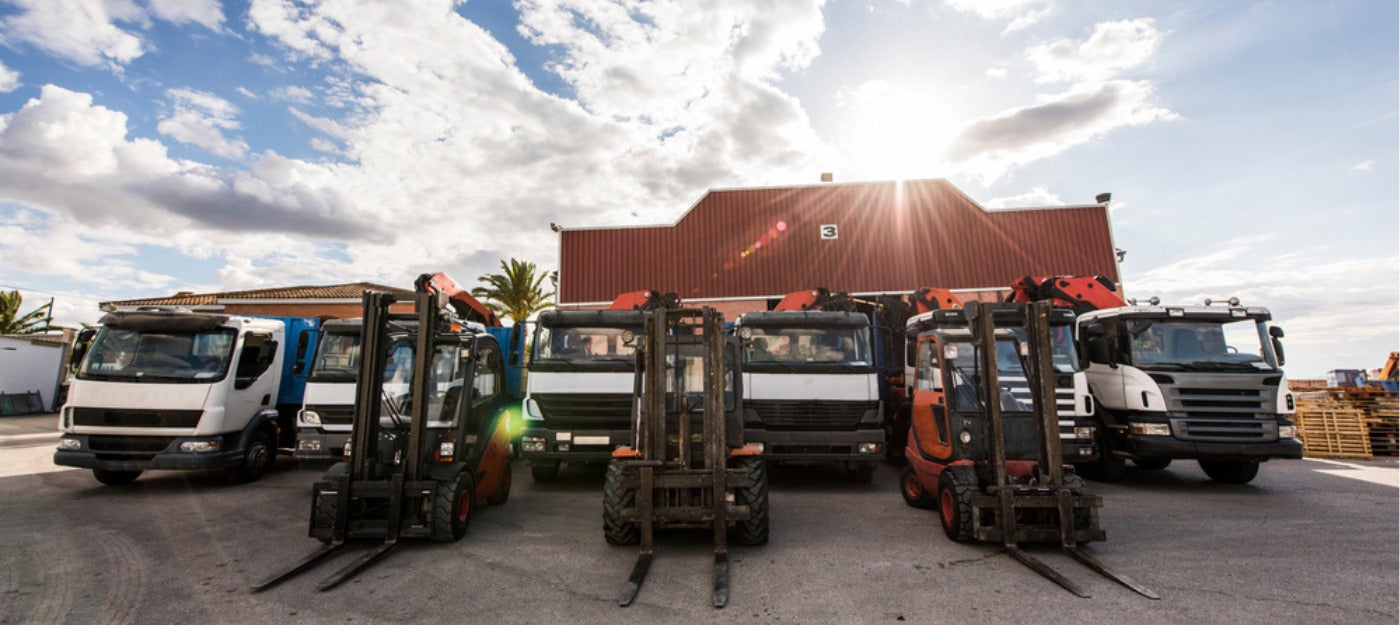 Fleet of trucks and forklifts outside of a warehouse facility